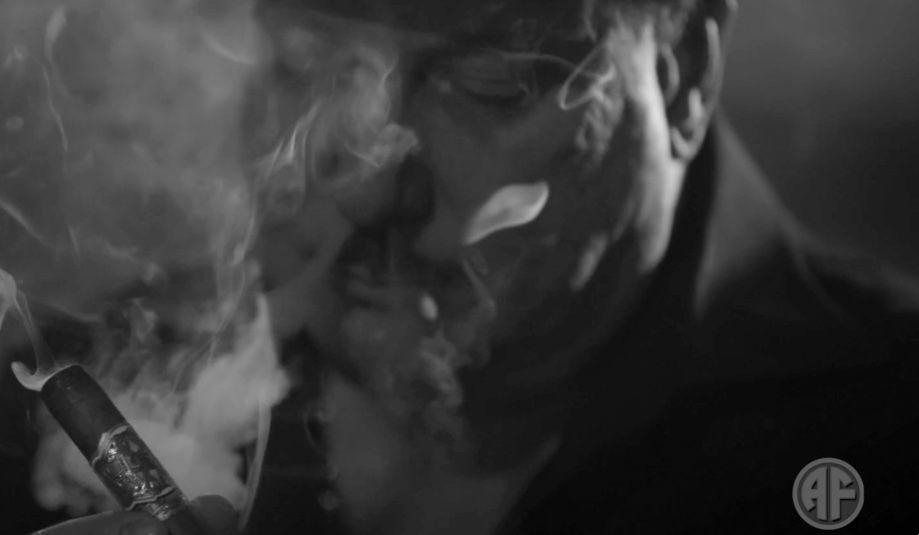Primer plano de hombre fumando un cigarro entre el humo